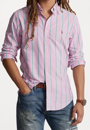 Gestreepte button-up shirt in roze en wit met teal accenten, voorzien van lange mouwen en een klassieke kraag, gecombineerd met versleten blauwe jeans.