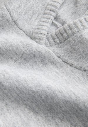 Szürke kötött pulóveranyag közeli felvétel, V-nyakkivágással, bordázott textúrával és puha, sima gyapjúkeverék felülettel.