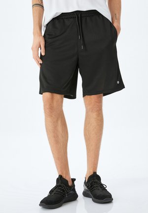 Sorte atletiske shorts med elastisk talje, snorelukning, sidelommer og et glat, letvægtsstof.