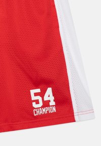 Pantaloni sportivi rossi in rete con pannelli laterali bianchi. Presentano un audace testo bianco "54 CAMPIONE" sulla gamba sinistra in basso. Tessuto traspirante.