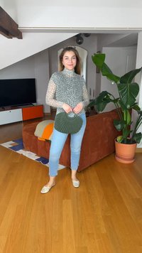 Γυναίκα που στέκεται σε ένα σαλόνι, φορώντας μακρυμάνικη μπλούζα με λεοπάρ σχέδιο, μπλε τζιν, κρεμ μπαλαρίνες και κρατώντας μια πράσινη στρογγυλή τσάντα.