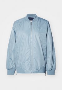 Světlounce modrá bomber bunda z hladké, lesklé látky s žebrovanými manžetami a lemem, zapínáním na zip a bočními kapsami. Jemné logo na hrudi.