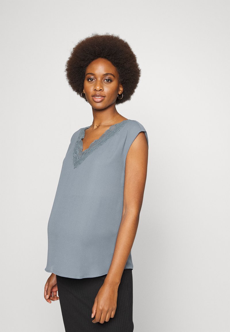 Top sem mangas azul claro com decote em V e renda, apresentando um corte solto e uma textura suave, combinado com uma parte de baixo riscada em preto.