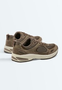 Brown suede and mesh sneakers with beige cushioned soles, lace-up design, and heel pull tabs, shown from a rear side angle on a white background.