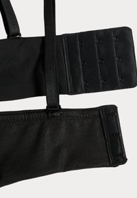 Bretelles de soutien-gorge en tissu noir et fermetures ajustables à crochets avec trois rangées de crochets pour ajuster la taille sur fond blanc.