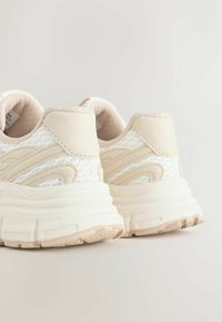 Sneakers da donna in bianco e beige. Caratterizzate da tomaia in mesh, collarino imbottito e suola texturizzata per una migliore aderenza. Tallone arrotondato con finitura morbida.