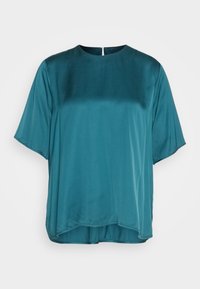 Teal, kortærmet bluse med en glat, blank tekstur. Rund halsudskæring og en let asymmetrisk kant. Har en diskret lukning bagpå.
