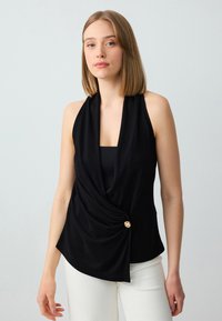 Top avvolgente nero realizzato in tessuto morbido, con scollatura a V profonda, design drappeggiato e dettaglio decorativo con bottone dorato in vita.