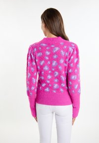 Maglione fuzzy rosa con macchie viola, collo rotondo, polsini e orlo a coste. Tessuto spesso e texturizzato, maniche lunghe e vestibilità leggermente over-size.