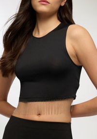 Czarny top crop w dopasowanym fasonie o gładkiej fakturze, z metalicznym frędzlem na dolnej krawędzi. Prosta bezrękawnikowa konstrukcja.