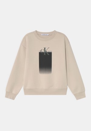 Beige sweatshirt met ronde hals en lange mouwen, met een zwart vervaagd rechthoek en het "ck Calvin Klein Jeans"-logo op de borst.