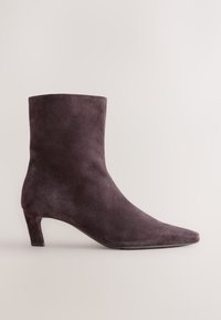 Suede ankle boot in dark purple with a pointed toe and a low, curved heel. Smooth texture with no visible hardware or patterns.