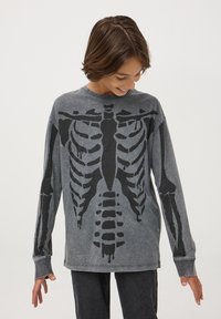 Szara koszulka z długim rękawem z czarnym grafikiem czaszki na przodzie. Wykonana z miękkiego materiału, o luźnym kroju i ściągaczach przy mankietach.