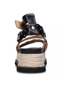 Sandal in pelle nera con cinturini beige, caratterizzata da borchie decorative e una suola a zeppa avvolta in juta. Suola testurizzata per una migliore aderenza.