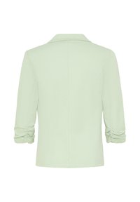 Veste vert clair avec manches trois-quarts froncées, coutures arrière cintrées et col cranté, vue de dos.