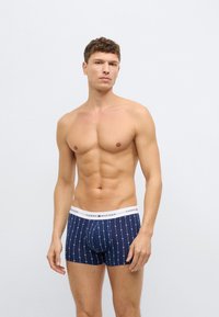 Marineblaue Boxershorts mit einem gepunkteten Muster und einem weißen Bund mit "TOMMY HILFIGER"-Logo. Hergestellt aus weichem, elastischem Stoff.