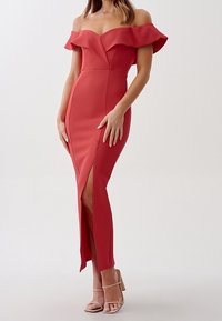 Rød off-shoulder kjole med flæser, tætsiddende facon, sideslids, struktureret stof, båret med nude strappy hæle.