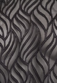 Schwarzer Stoff mit einem Wellenmuster und erhabenen, strukturierten Linien. Das Design erzeugt Tiefe und visuelles Interesse vor einem glatten Hintergrund.