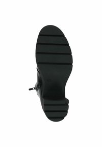 Černá podrážka boty s horizontálními drážkami a zipem na boku, vystavená na bílem pozadí.