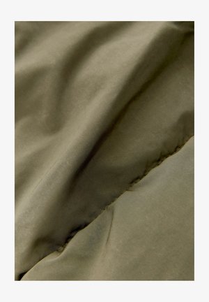 Tejido verde oliva que muestra una textura suave y mate con ondulaciones sutiles y una costura visible. Material liviano y flexible.