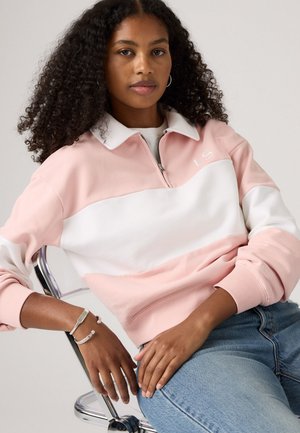 Sweatshirt rose clair et blanc à fermeture éclair quart avec des poignets côtelés. Texture lisse, arborant un petit logo "LS" sur la poitrine et un col.
