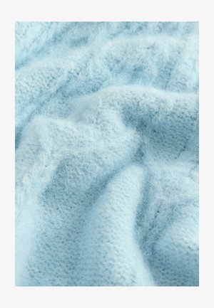 Tissu tricoté bleu clair avec une texture douce et duveteuse, présentant un mélange de motifs et de points qui créent de la profondeur et de l'intérêt visuel.
