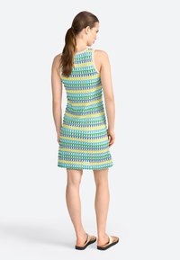 Abito senza maniche con un vivace motivo geometrico in blu, verde e giallo. Lunghezza a metà coscia con una silhouette aderente.