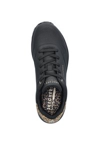 Zwarte sportschoen met een gladde bovenkant, geperforeerd ontwerp en vetersluiting. Dierenprintvoering en branding op de tong zijn opvallende details.