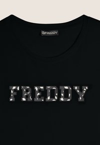 Camiseta negra con cuello redondo que presenta la palabra "FREDDY" en letras texturizadas y con patrón en gris, blanco y negro.
