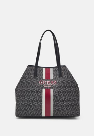 Torba tote z ciemnoszarym wzorem geometrycznym, pionowymi czerwonymi i białymi paskami oraz wytłoczonym logo "GUESS EST. 1981" z przodu. Czarne uchwyty.