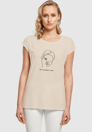 Beige bomull T-skjorte med korte ermer og rund hals. Den har en minimalistisk svart linjetegning av et ansikt og trykket tekst.