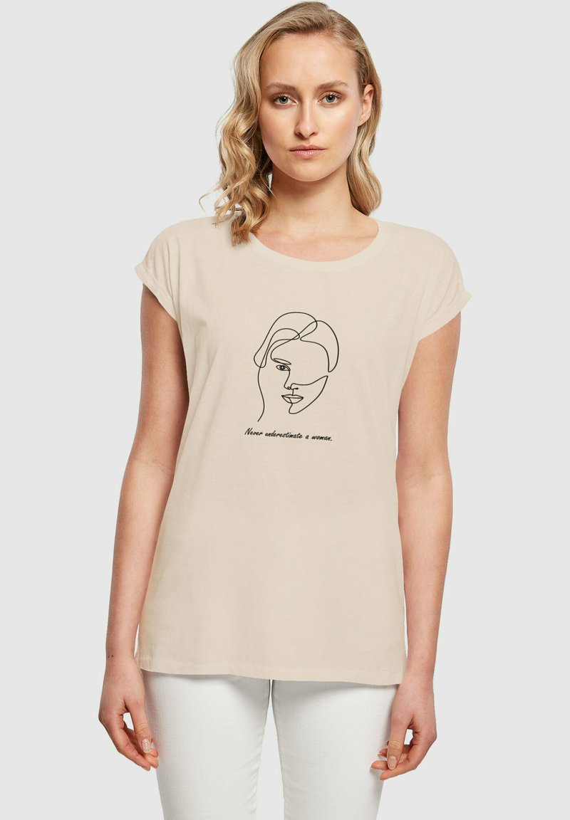 Beige Baumwoll-T-Shirt mit kurzen Ärmeln und rundem Halsausschnitt. Mit einer minimalistischen schwarz-weißen Zeichnung eines Gesichts und bedrucktem Text.