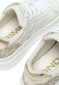 Sneakers in pelle bianca con un accento beige testurizzato e dorato glitterato. Presentano lacci bianchi e una linguetta imbottita. Brand sul plantare in oro.