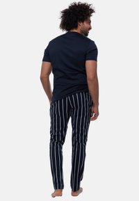 Marinblå crew neck t-shirt i kombination med svart och vit randiga pyjamasbyxor. Tyget ser mjukt ut; byxorna har en slim fit-design.