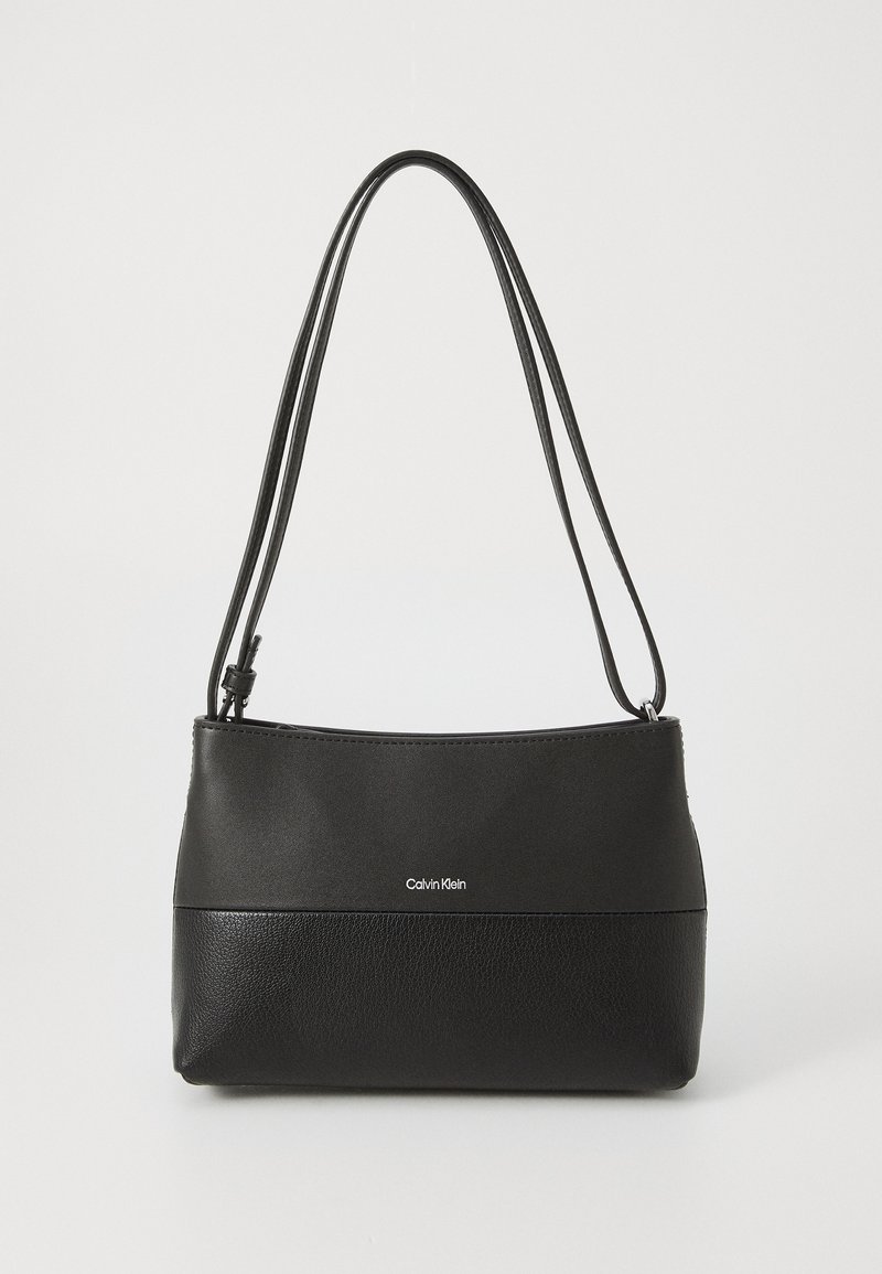 Carteira preta da Calvin Klein com duas alças para o ombro, uma parte superior lisa, uma parte inferior texturizada e um logotipo centralizado na frente.