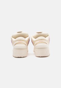 Bežad spordijalad su sile skina, kõverate kujundite ja lillade aktsentidega kandadel. Sisaldab tugevdatud kontsa ja reljeefset logo detaili.