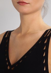 Top nero senza maniche con scollatura profonda a V, caratterizzato da aperture sui cinturini e tessuto a maglia testurizzato.