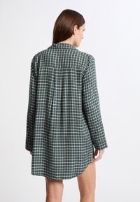 Camicia a maniche lunghe con un motivo a quadri verde e bianco, caratterizzata da un colletto classico, orlo dritto e vestibilità ampia. Realizzata in tessuto morbido.