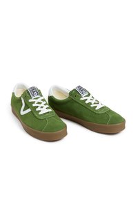 Baskets en daim vert avec lacets blancs, patch logo blanc contrastant et semelle extérieure en caoutchouc marron. Bout arrondi et design profil bas.