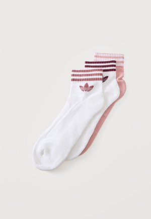 Trzy pary skarpetek Adidas do kostek w białych i różowych odcieniach, każda z prążkowanymi ściągaczami i logo Adidas przy górze. Skarpetki są starannie ułożone w stos.