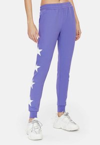 Paarse sweatpants met een tapered fit, met witte sterpatronen aan de buitenzijde en een elastische tailleband voor comfort.