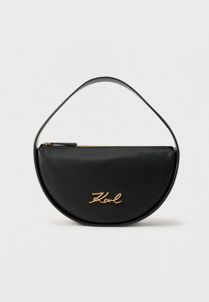 Μαύρη ημικυκλική τσάντα χειρός με επάνω φερμουάρ και χρυσό λογότυπο "Karl" στο μπροστινό μέρος, με μαύρη λαβή που ταιριάζει.