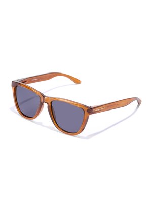 Braune transparente Plastiksunglasses mit dunkelgrauen Gläsern, quadratischer Form und einem Metallelement an den Bügeln. Auf der Seite steht "HAWKERS".