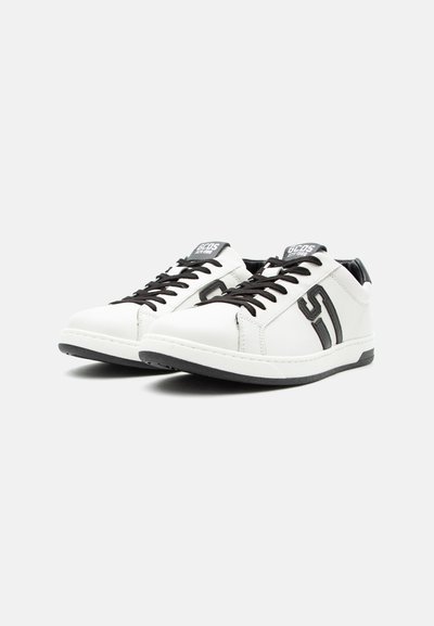 Λευκά sneakers χαμηλού προφίλ με μαύρα κορδόνια, μαύρο λογότυπο στο πλάι και μαύρη σόλα, τοποθετημένα δίπλα-δίπλα σε λευκό φόντο.