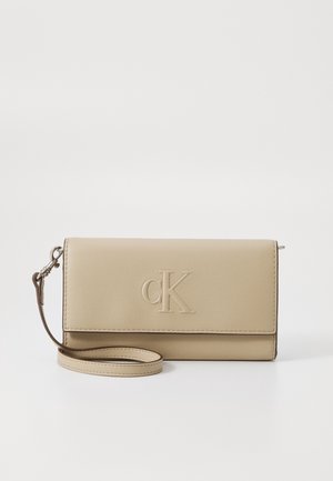 Beige leren polswallet met geperst "cK"-logo aan de voorkant en afneembare band aan de linkerkant.
