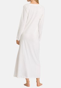 Lunga camicia da notte bianca con maniche lunghe, caratterizzata da un colletto rotondo e una vestibilità ampia che scende fino alle caviglie, realizzata in tessuto morbido e liscio.