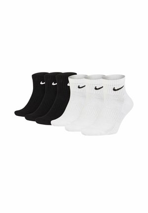 Drei Paare schwarze und drei Paare weiße Knöchelsocken mit schwarzen und weißen Nike Swoosh-Logos an den Bündchen.