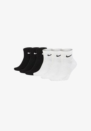 Drei Paare schwarze und drei Paare weiße Knöchelsocken mit schwarzen und weißen Nike Swoosh-Logos an den Bündchen.