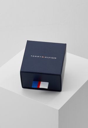 Boîte bleu marine Tommy Hilfiger avec logo sur le dessus et une languette en tissu bleu, blanc et rouge sur le devant du tiroir.