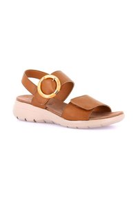 Sandal in pelle marrone con cinturini regolabili, accentuazione circolare dorata, punta aperta e suola beige imbottita. Design piatto per il massimo comfort.